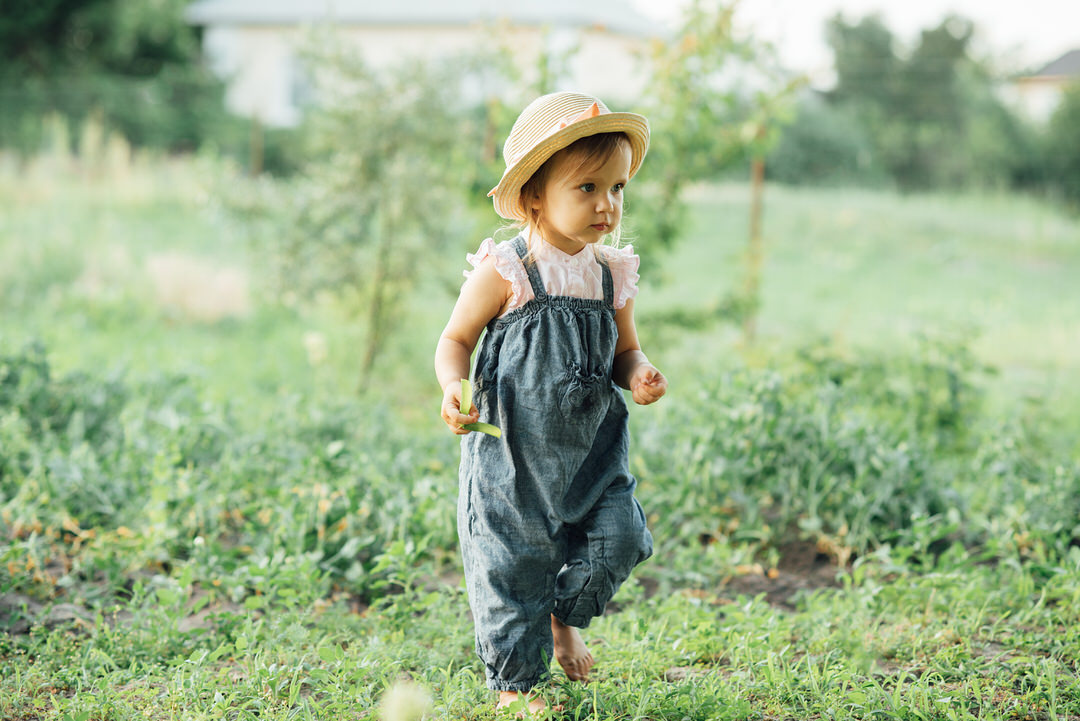 Portrait of child girl eating pea pod outdoors. Girl harvesting peas in garden summer. Helthy eating for kid. Gardening, gardener, Little farmer child lovely girl with picked vegetables Magdalena Michałuszko Fizjomag Fizjoterapeutka Fizjoterapia dzieci uroginekologiczna Ndt-Bobath dla dzieci FITS Skoliozy trójpłaszczyznowa stóp Płoskie Zamość Lubelskie
